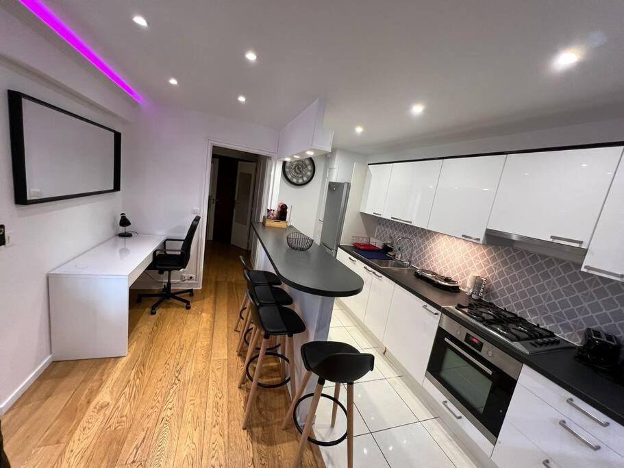 a kitchen with white cabinets and black counter tops at Superbe appartement meublé avec parking in Saint-Gratien