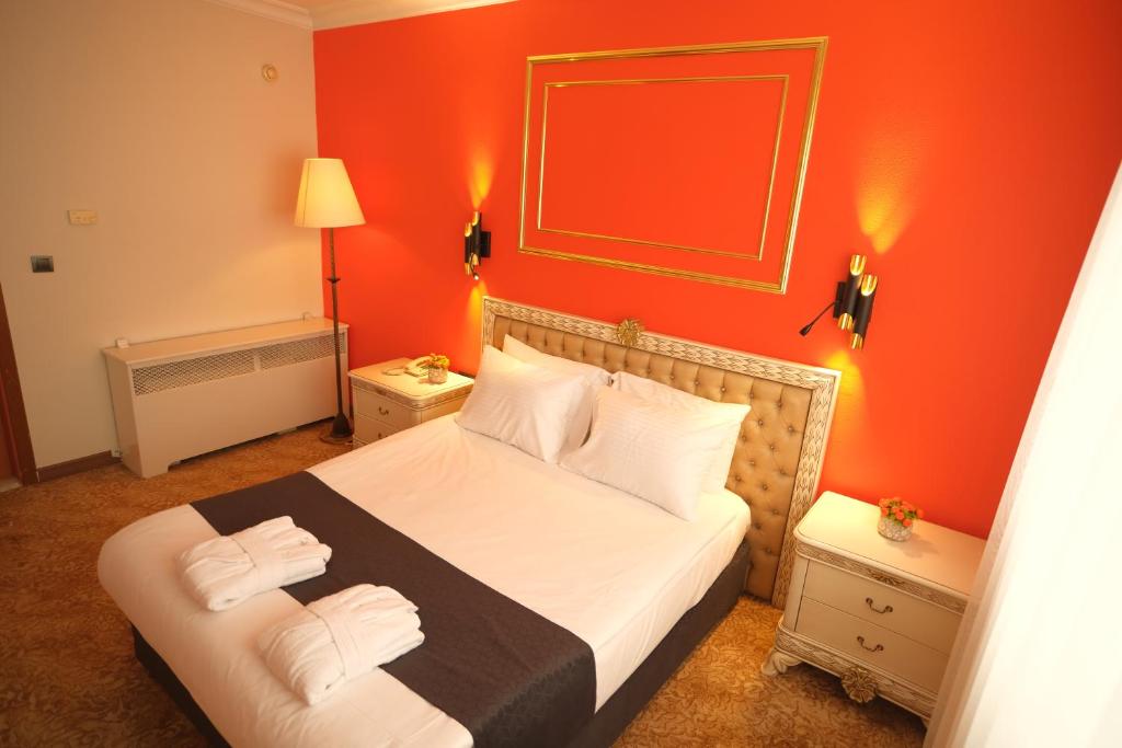 a bedroom with a bed with an orange wall at Malabadi Hotel in Diyarbakır