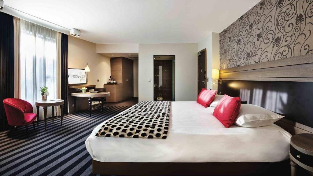 a hotel room with a large bed with red pillows at Van Der Valk Sélys Liège Hotel &amp; Spa in Liège