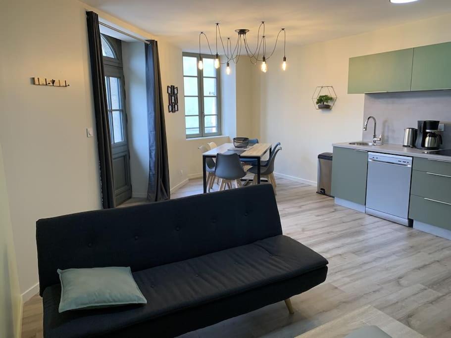 een woonkamer met een bank en een keuken bij Appartement Torii - Maulévrier Cholet Puy du Fou in Maulévrier