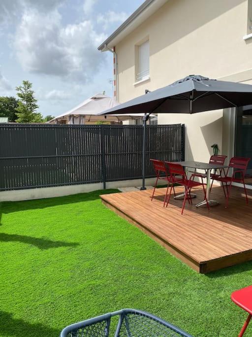 un patio avec une table, des chaises et un parasol dans l'établissement Maison à Gujan-Mestras au calme, à Gujan-Mestras