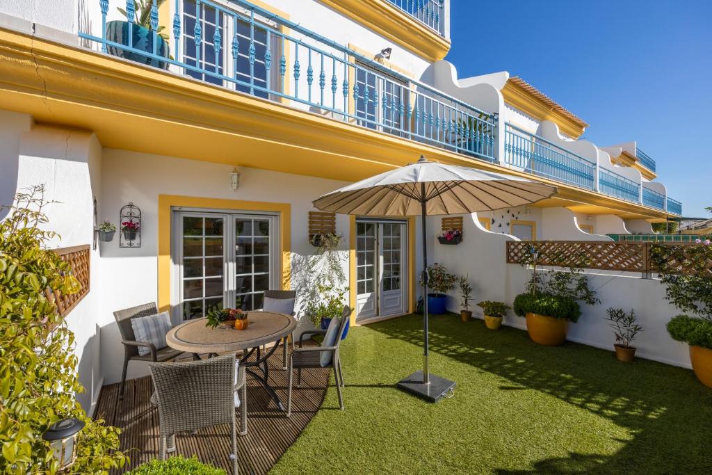 Un patio con una mesa y sillas y una sombrilla. en Vila Hortense, en Alvor