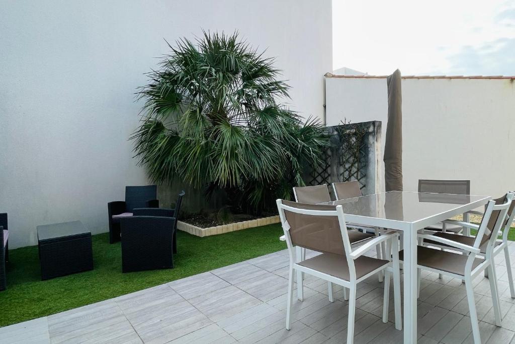 una mesa y sillas blancas y una palmera en Cozy cocoon of love with terrace and garden, en La Rochelle