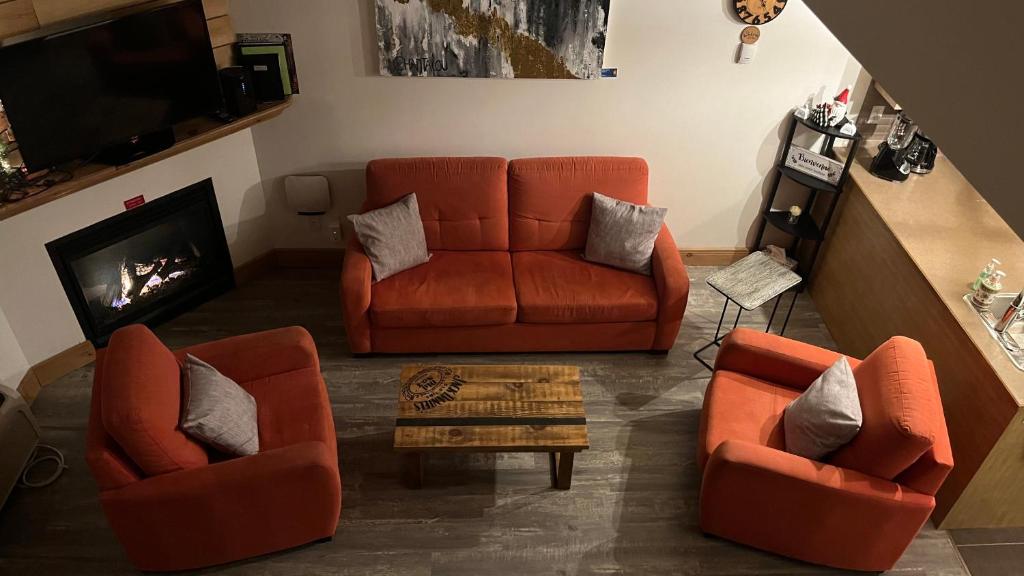 a living room with two orange chairs and a couch at Condo du Bonheur in Mont-Tremblant