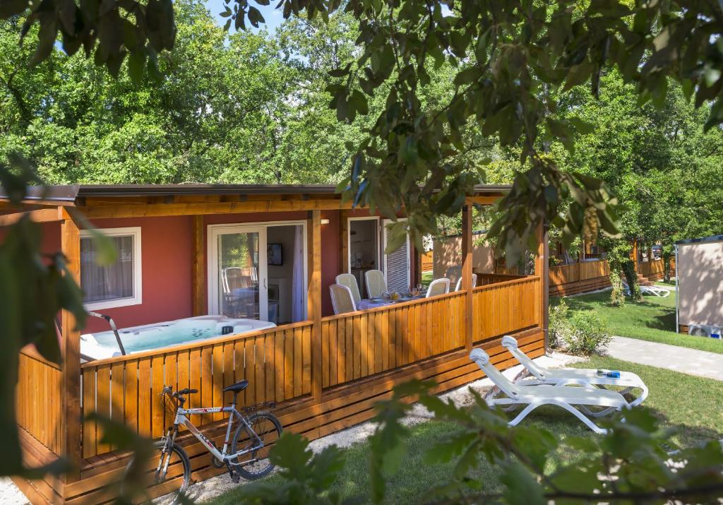 a house with a deck with a pool and a bike at Maistra Camping Valkanela Mobile homes in Funtana