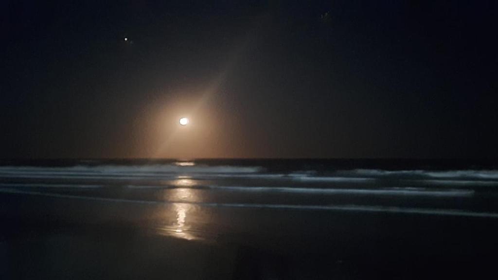 uma praia à noite com a lua à distância em Hotel.Aires de Libertad em San Bernardo