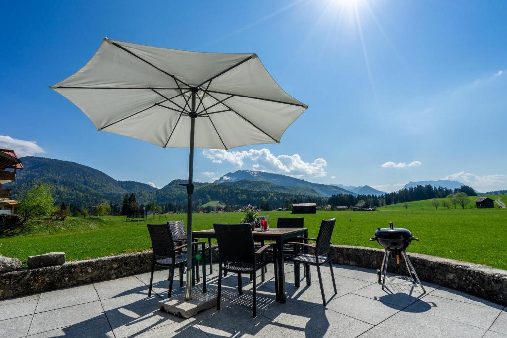 a table and chairs with an umbrella and a grill at Villa Pia in Reit im Winkl