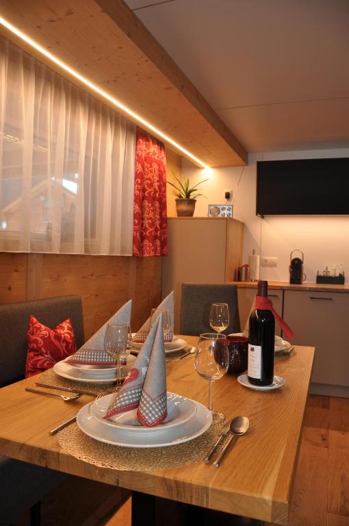 a wooden table with plates and wine glasses on it at Hotel Maroi in Wald am Arlberg