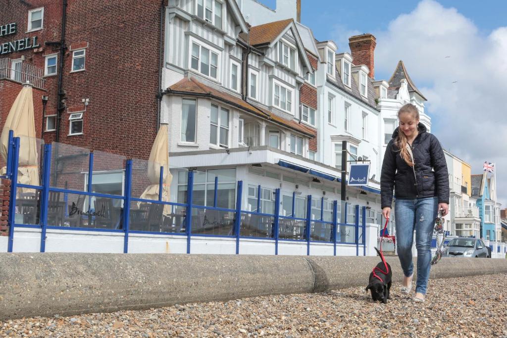 a woman walking a black dog on a leash at The Brudenell in Aldeburgh