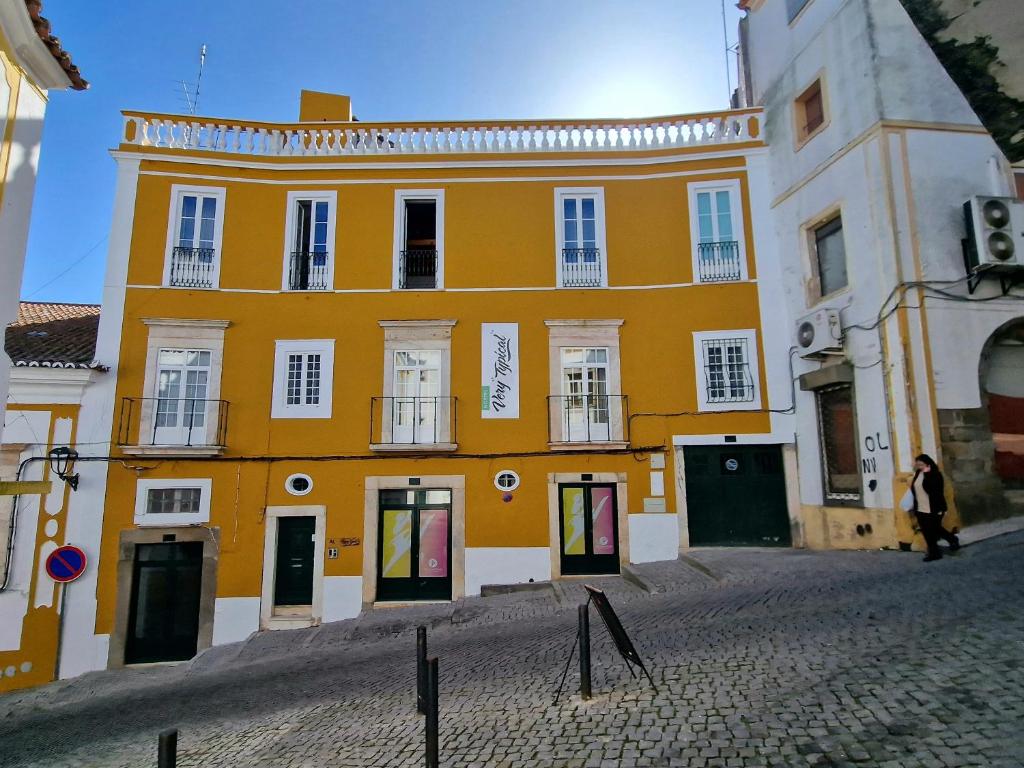 um edifício amarelo com janelas brancas numa rua em Very Typical - Alojamento Local em Elvas