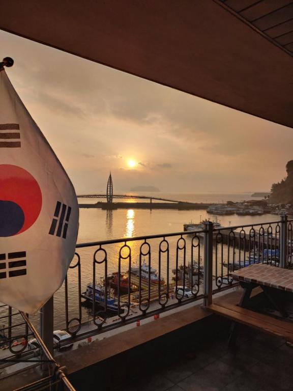 - un balcon offrant une vue sur un bateau de croisière au coucher du soleil dans l'établissement Seom Guesthouse, à Seogwipo