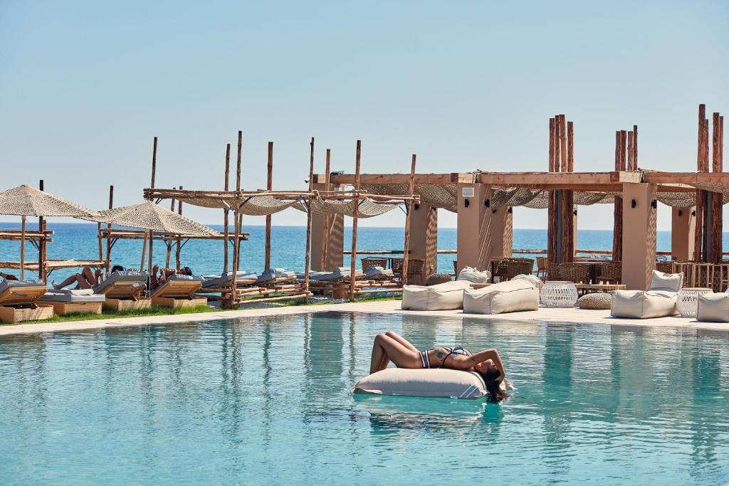 Una donna stesa in acqua in una piscina di La Mer Resort & Spa - Adults Only a Georgioupolis