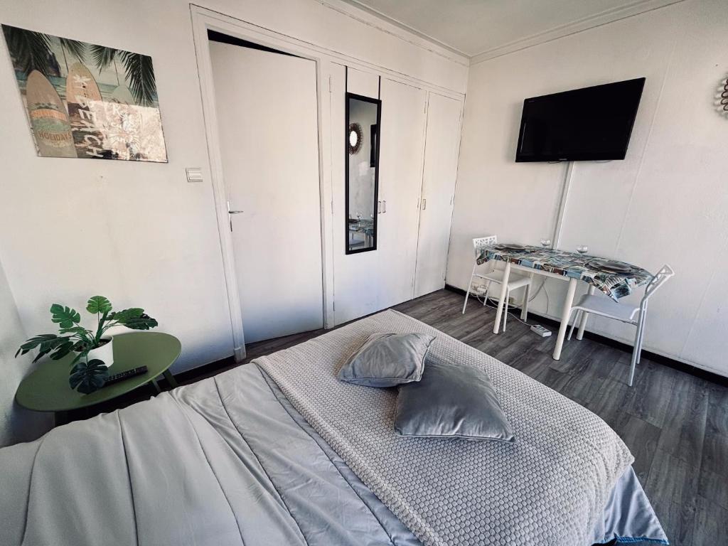 a bedroom with a bed and a table and a television at Superbe studio pour 2 à 20m de la plage - 27 in Canet-en-Roussillon