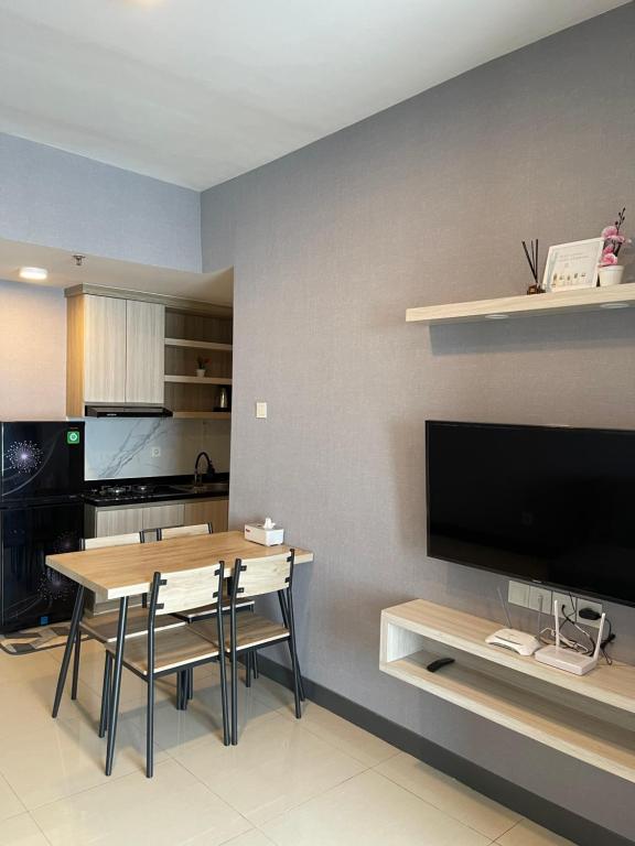 a kitchen and dining room with a table and a television at 2 BR I ANDERSON I 25floor I above pakuwon mall I the biggest shopping center in Surabaya