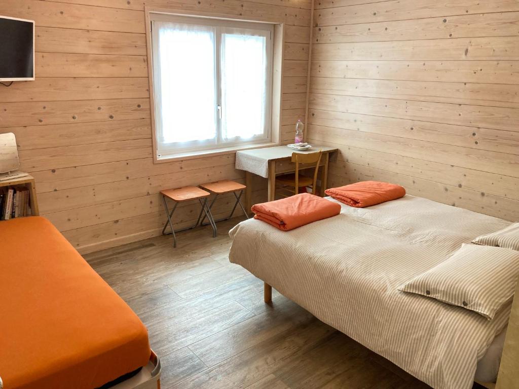 Habitación con 2 camas, escritorio y ventana. en Pedibosco Orange en Calalzo