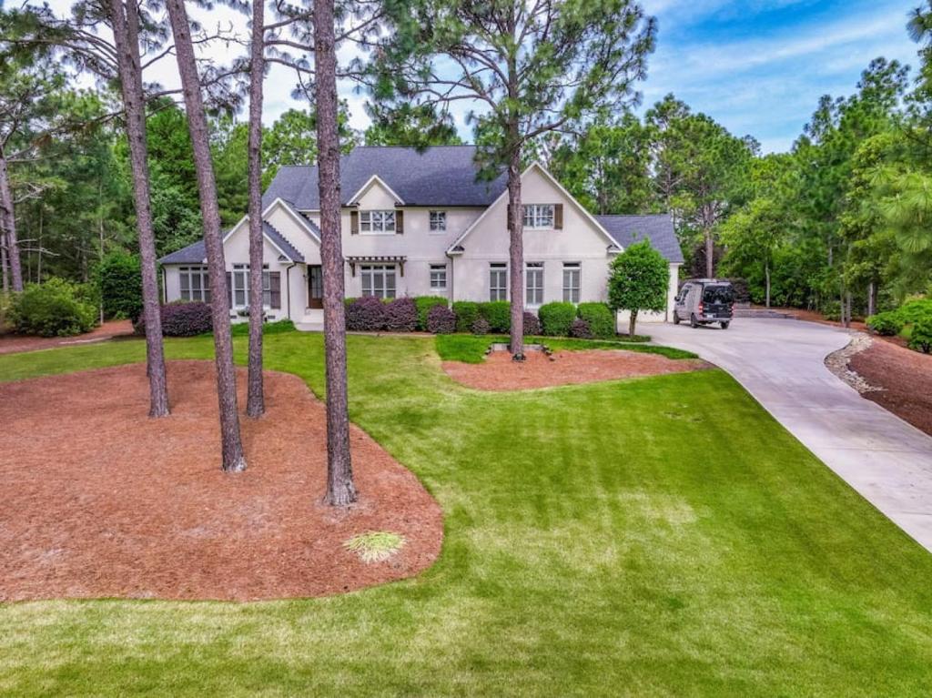 a white house with trees in front of a driveway at Sleeps 14 - Pinehurst in Pinehurst