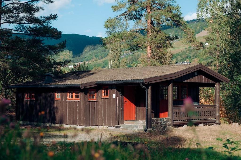 a small wooden cabin with a red door at Hunderfossen Cottages in Hafjell