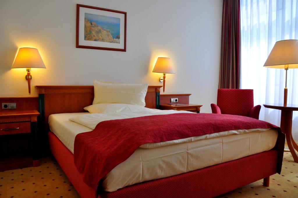 a hotel room with a bed with a red blanket at Hotel Steglitz International in Berlin