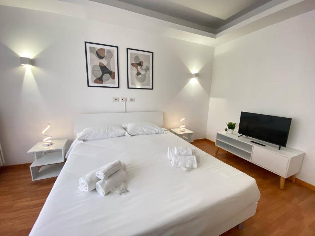 a white bedroom with a large white bed and a flat screen tv at Casa Relax 120 MQ con Metro in Rome