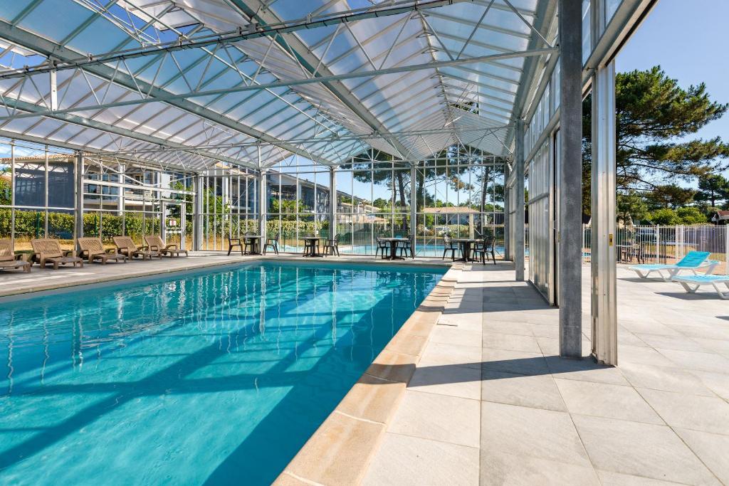 an indoor swimming pool with a glass roof at Lagrange Vacances L'Estuaire in Le Verdon-sur-Mer