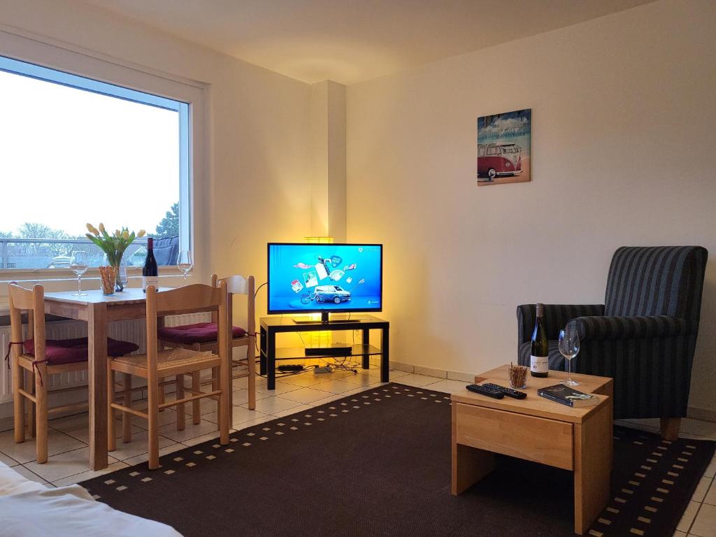 sala de estar con TV y mesa de comedor en Haus zur Dünenbake - Apartment 24, en Sankt Peter-Ording