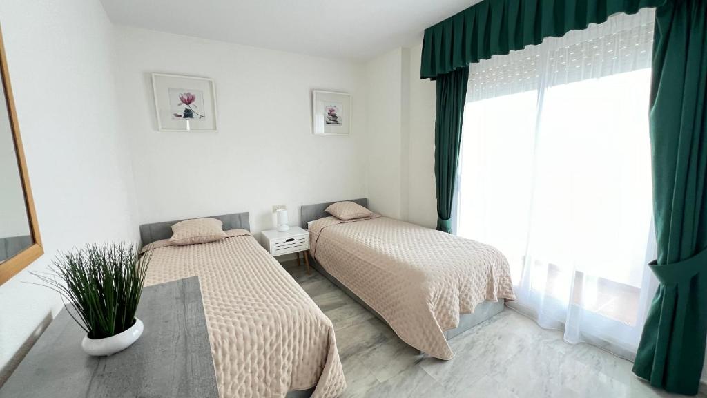 dwa łóżka w pokoju z oknem w obiekcie Costalita - 2 bedroom apartment 350m from the beach w mieście Estepona