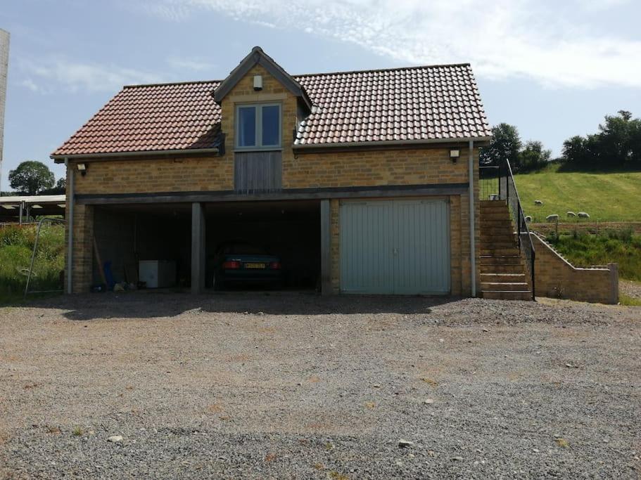 una casa con un garaje con un coche dentro en Farm Loft, en Shepton Mallet