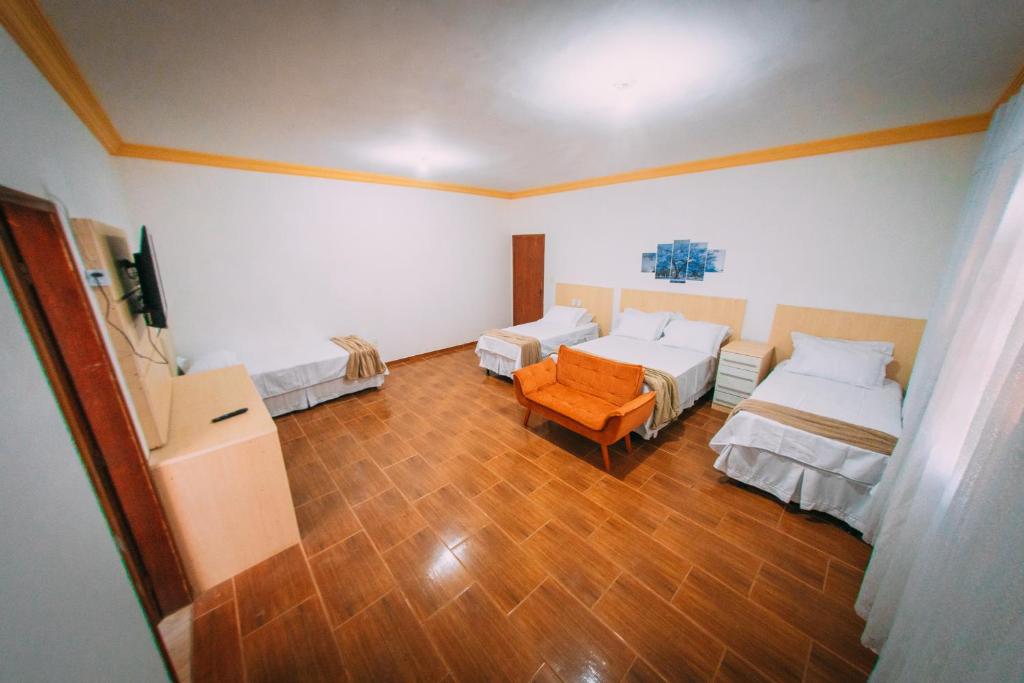 Habitación con 2 camas y una silla. en POUSADA ELMIRA´S BELA VISTA, en Ouro Branco