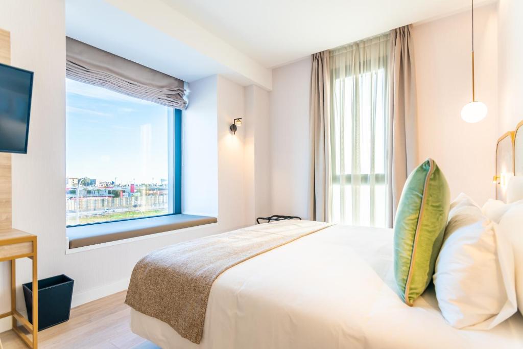 a bedroom with a large bed with a large window at Hotel Málaga Vibes in Málaga