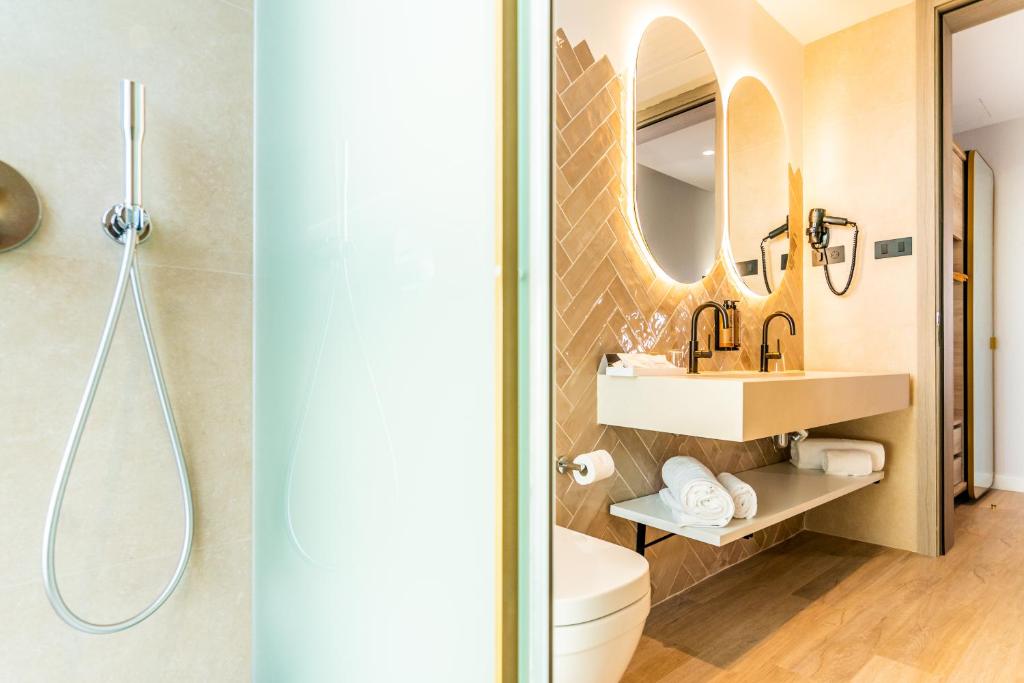 a bathroom with a sink and a toilet and a mirror at Hotel Málaga Vibes in Málaga