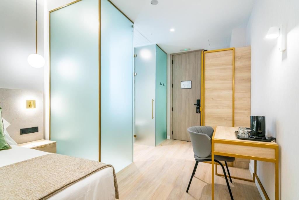 a bedroom with a desk and a bed and a table and chair at Hotel Málaga Vibes in Málaga