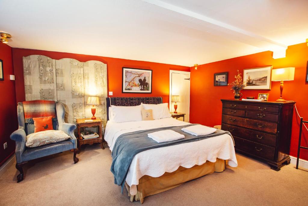 1 dormitorio con paredes de color naranja, 1 cama y 1 silla en Cosy Stable at Oak Farm en Usk