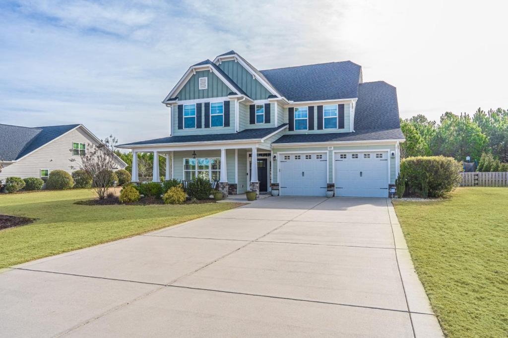 a house with a blue roof and a driveway at Sleeps 8- In Whispering Pines 