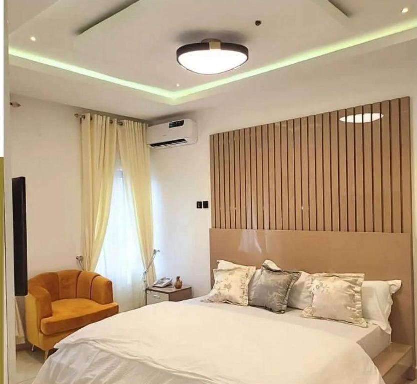 a bedroom with a large bed and a chair at Supreme Apartments in Ibadan