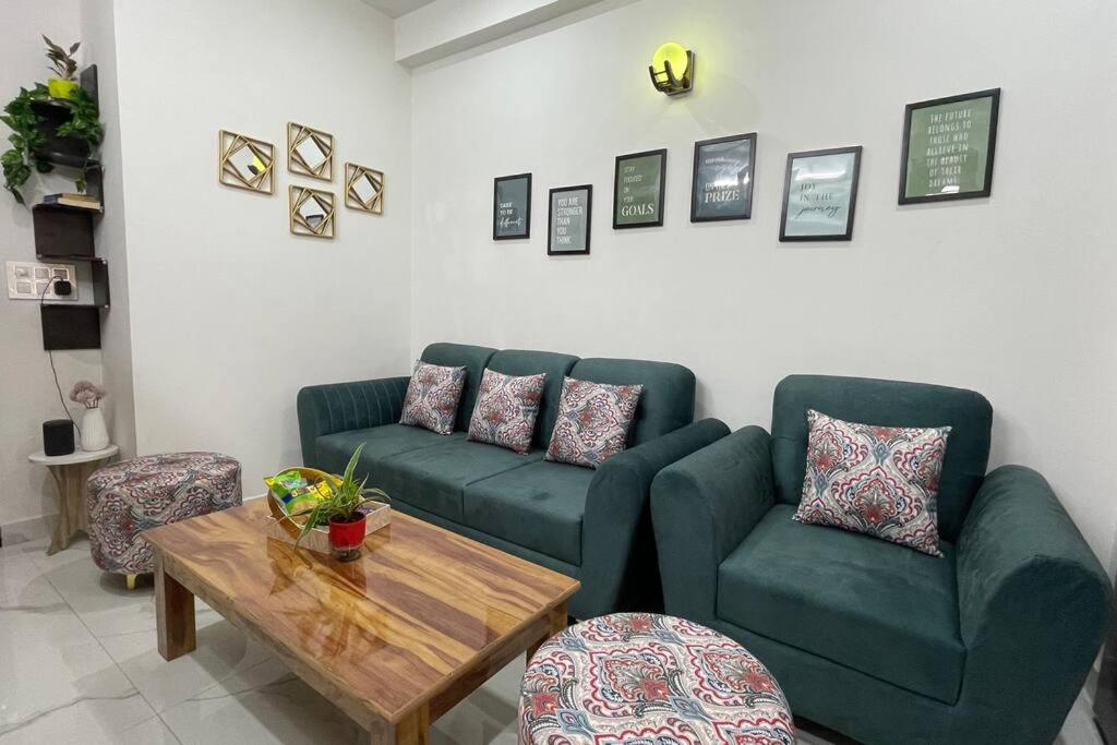 una sala de estar con 2 sofás verdes y una mesa. en Compact & Cozy 2BHK@GolfCourseRoad, en Gurgaon