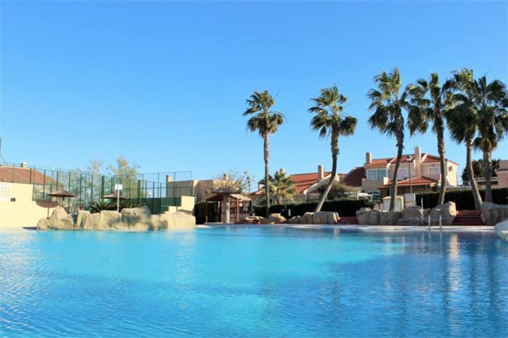 una grande piscina con palme sullo sfondo di Stunning Duplex with Sea Views a Gran Alacant