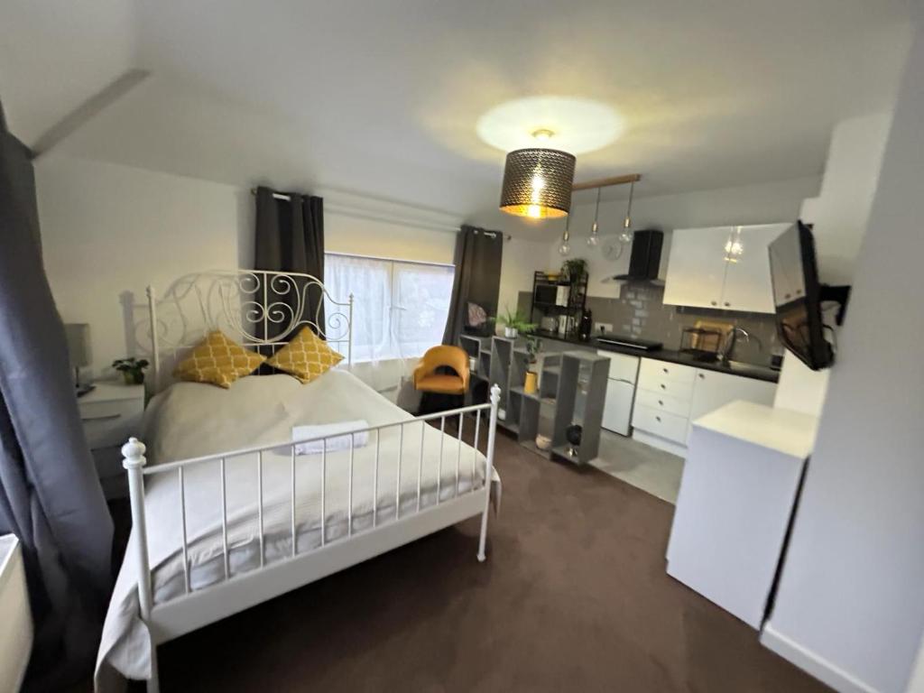 a bedroom with a white bed and a kitchen at PRESTON ROOM LET 8 in Yeovil