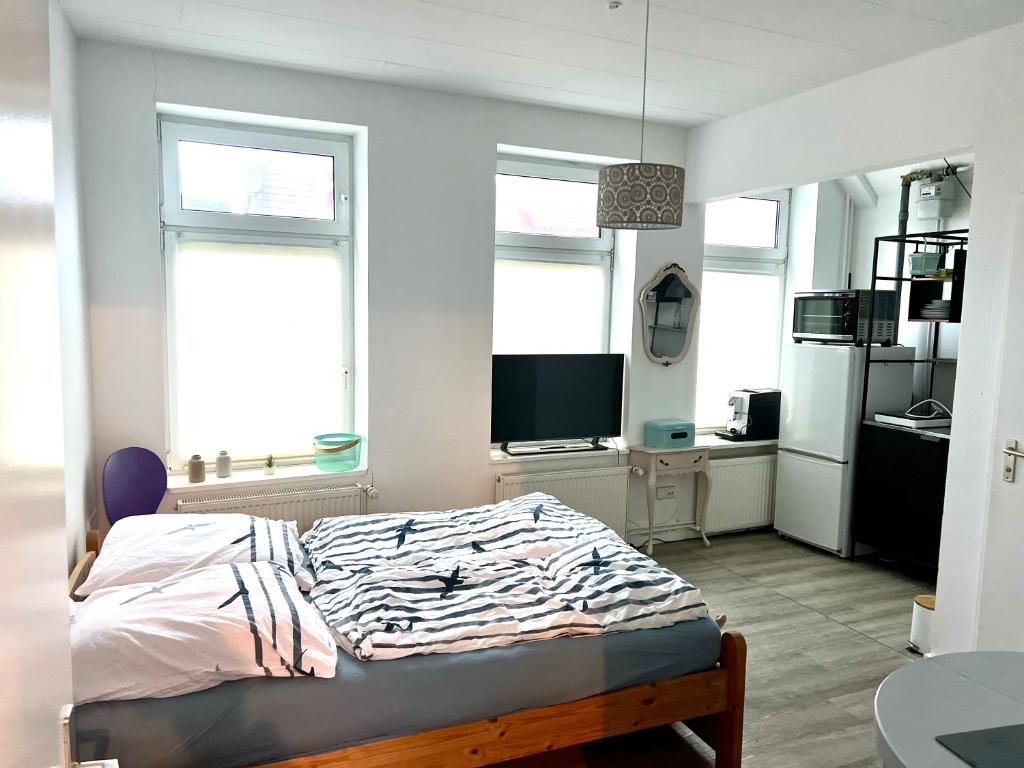 a bed in a room with two windows and a television at Ferienwohnung EbbeFlutMeer in Husum