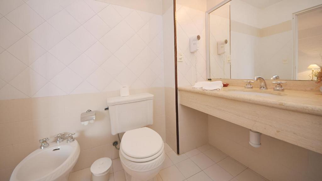 Un baño blanco con inodoro y lavabo. en Bagu Villa de Mar, en Punta del Este