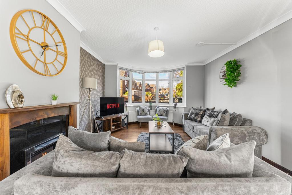a living room with a couch and a clock on the wall at Stylish Nottingham House - Parking - Garden in Nottingham