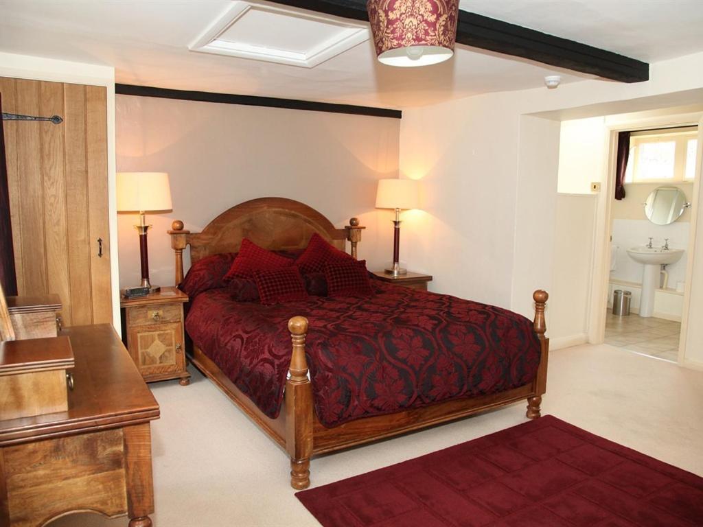 a bedroom with a large bed with a red bedspread at The Collyweston Slater in Collyweston