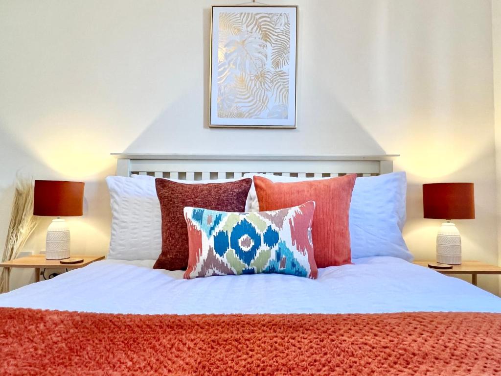 un letto con cuscini rossi e bianchi e 2 lampade di Bright, stylish flat in Hatfield sleeps 4 a Hatfield