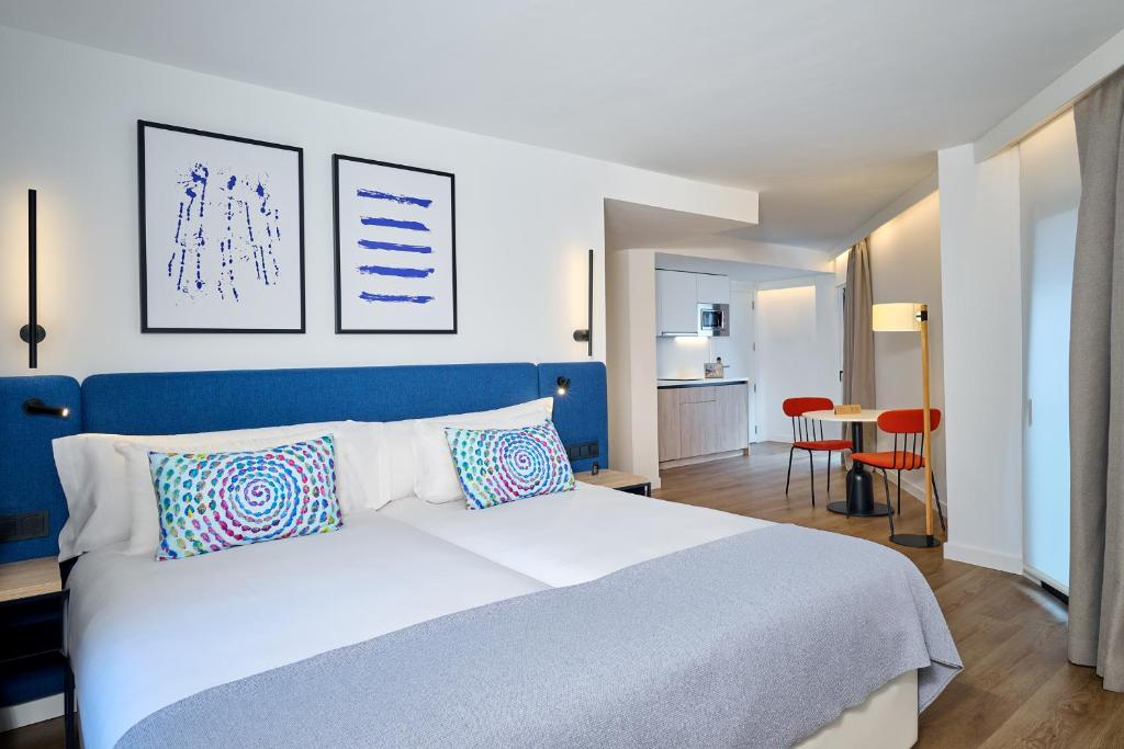 a bedroom with a white bed and a blue headboard at Apartamentos Luna Suites Granada in Granada