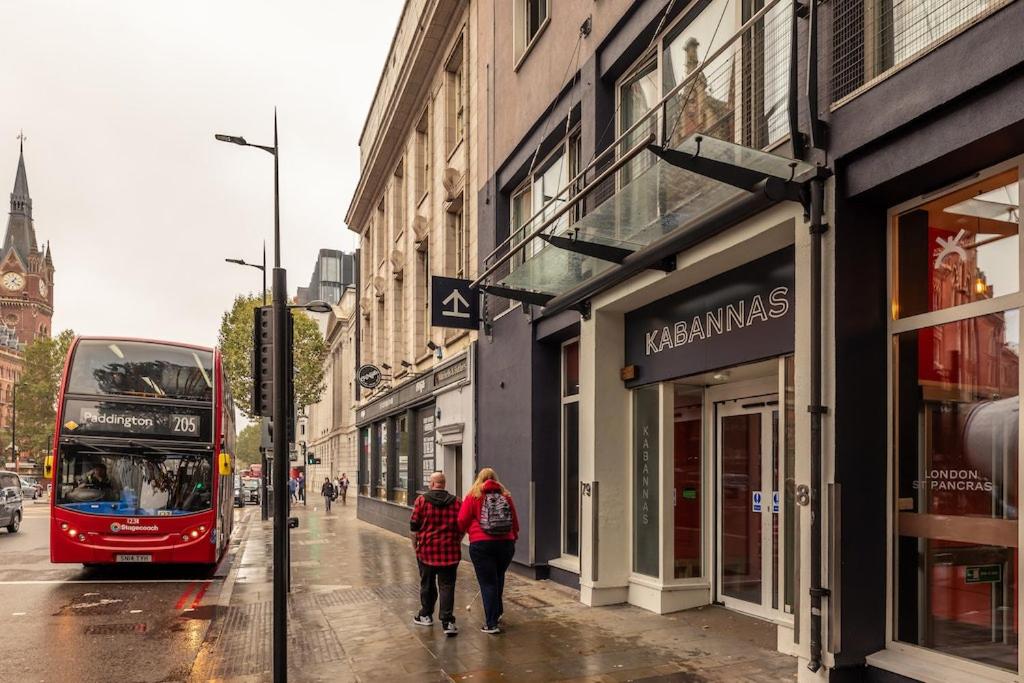 倫敦的住宿－Kabannas London St Pancras，两个人乘坐公共汽车沿着城市街道走