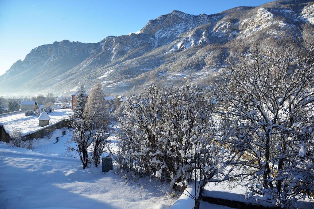 a snow covered hill with trees and a mountain at La Maison Abeil in LʼArgentière-la-Bessée