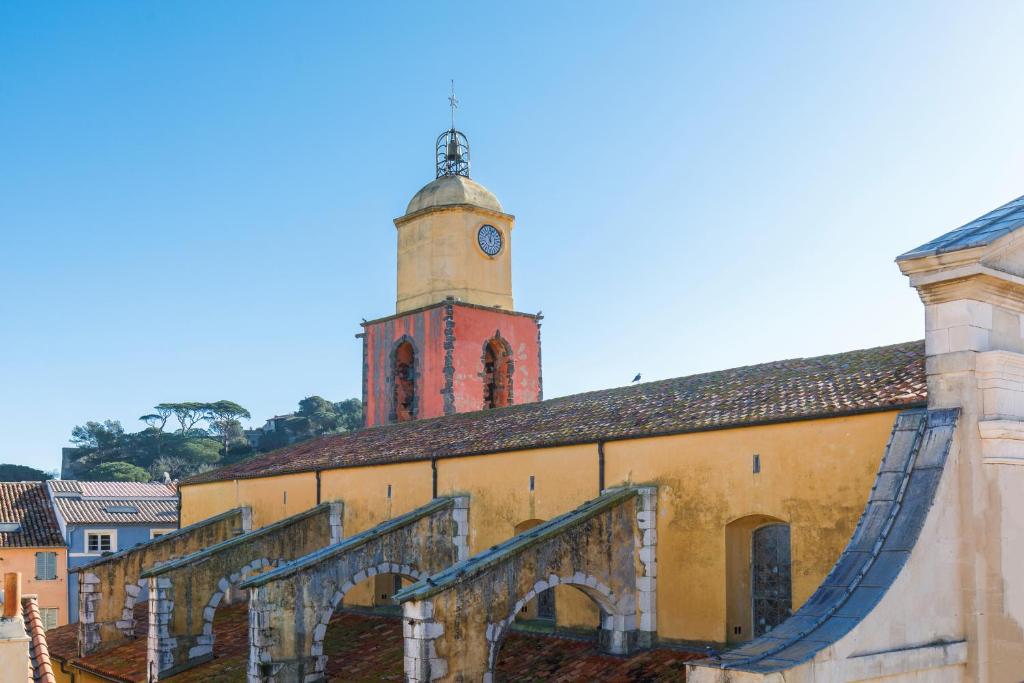 un bâtiment avec une tour dotée d'une horloge. dans l'établissement L'Appartement De Sophie YourHostHelper, à Saint-Tropez