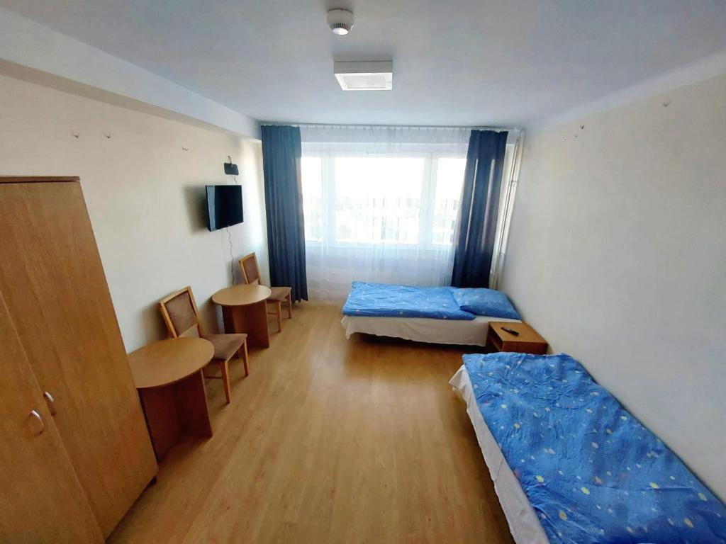 um pequeno quarto com duas camas e uma mesa em Pokoje Urzędnicza Kielce em Kielce