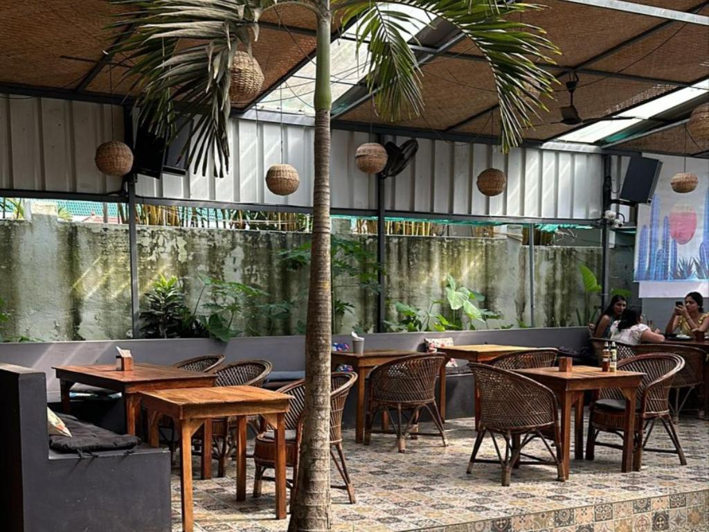 a restaurant with tables and chairs and a palm tree at Mad about Coco Yoga & Beach Retreat in Varkala