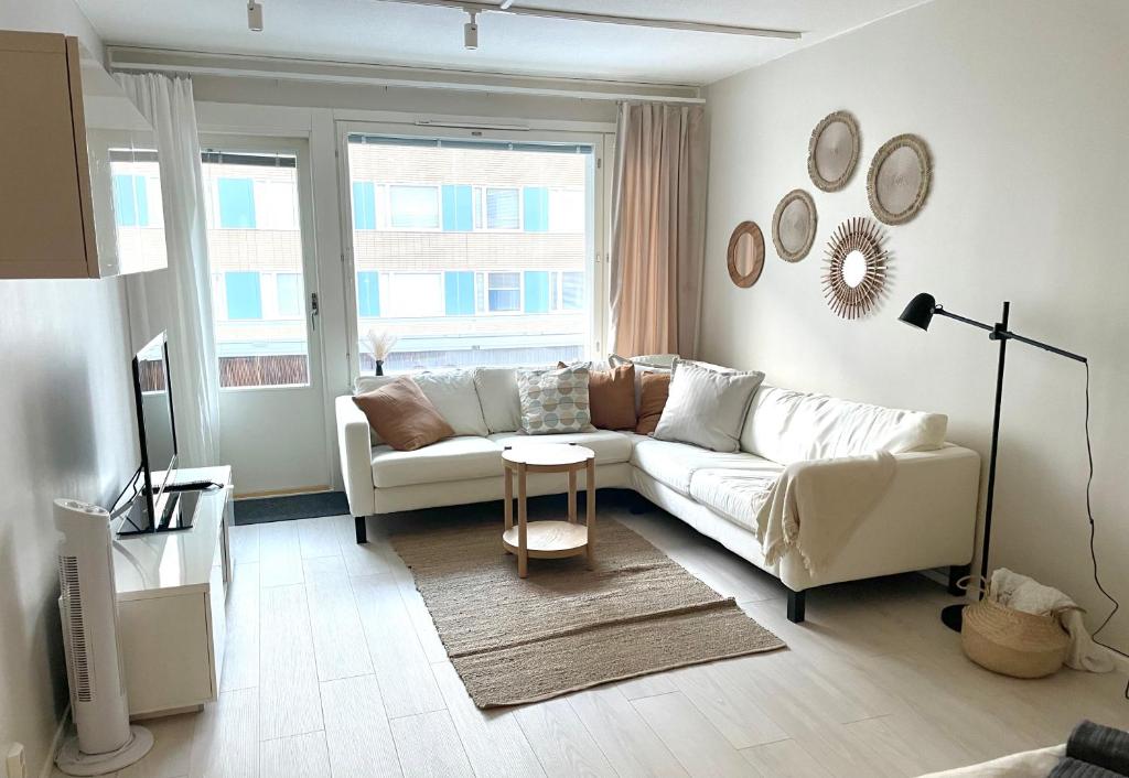 a living room with a white couch and a table at Avara keskusta asunto + oma ilmainen parkkipaikka in Tampere