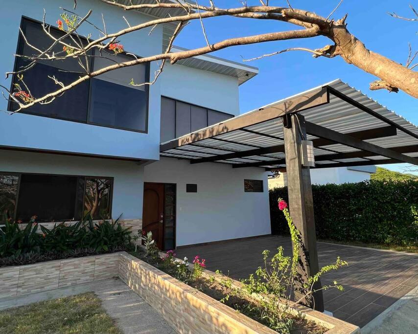 a white house with a wooden pergola at Tropical Hideaway with SharePool in Secure Condo, LIR in Guanacaste